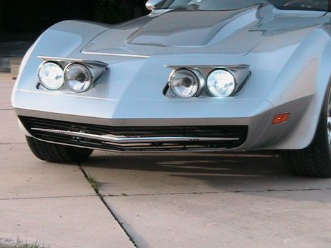1976 Chevrolet Corvette - Front view of a silver 1976 Chevrolet Corvette, its iconic pop-up headlights and grille.