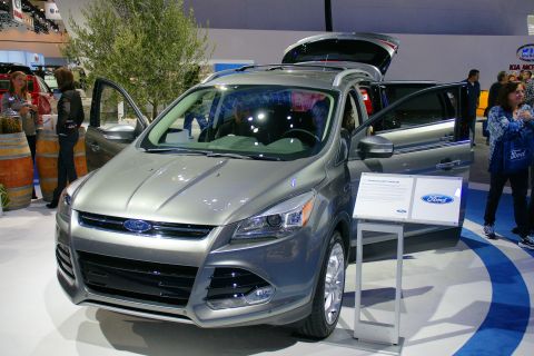 1993 Ford Taurus - A Ford Escape is displayed with its doors and trunk open at an auto show, with informational signage nearby.