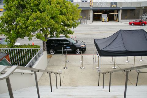 1993 Ford Taurus - A black Ford Explorer SUV is parked next to a black tent, with a red car driving by in the background.
