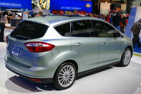 1993 Ford Taurus - A light blue Ford C-Max Hybrid is displayed at an auto show, with people in the background.