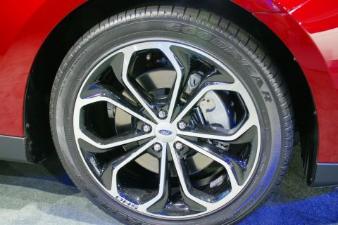 1993 Ford Taurus - Close-up of a red vehicle's front wheel a multi-spoke rim with a Ford emblem and 'SHO' lettering.