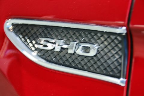 1993 Ford Taurus - Close-up of a chrome SHO badge on the fender of a red vehicle.