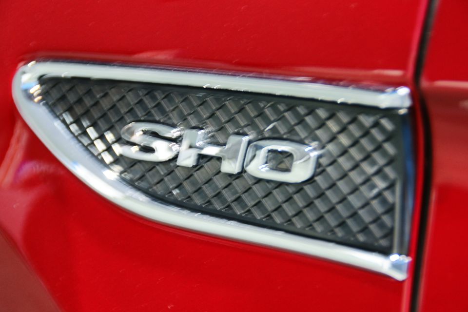 Red car fender with a chrome SHO badge over a black grille
