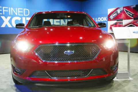 1993 Ford Taurus - A red Ford sedan is displayed at an auto show with promotional materials in the background.