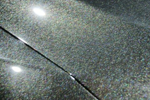 1993 Ford Taurus - Detail of dark, sparkling paint finish on a vehicle panel, showing a distinct seam line.
