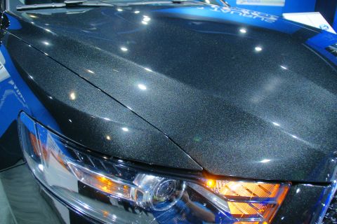 1993 Ford Taurus - Close-up of a dark metallic car's front end, highlighting the headlight and hood.
