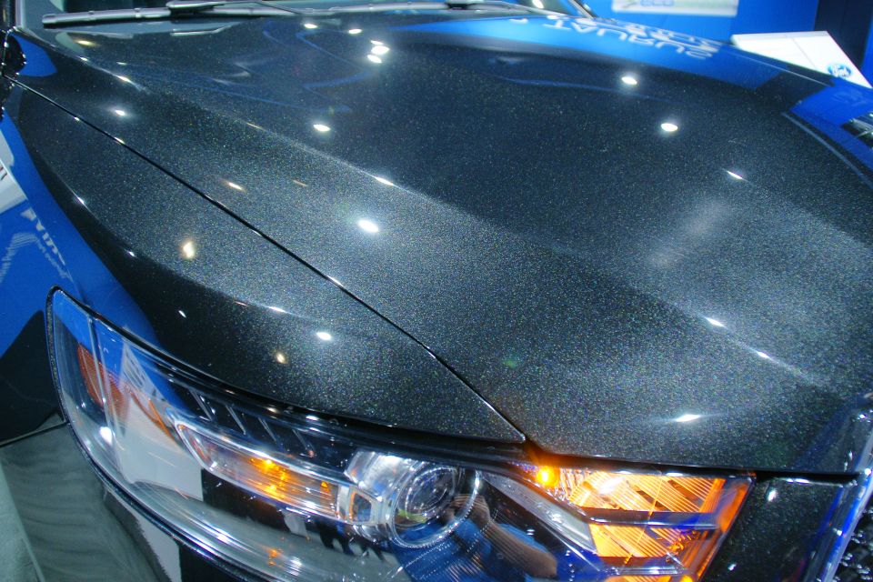 Dark metallic car hood and headlight assembly, showing the grille detail
