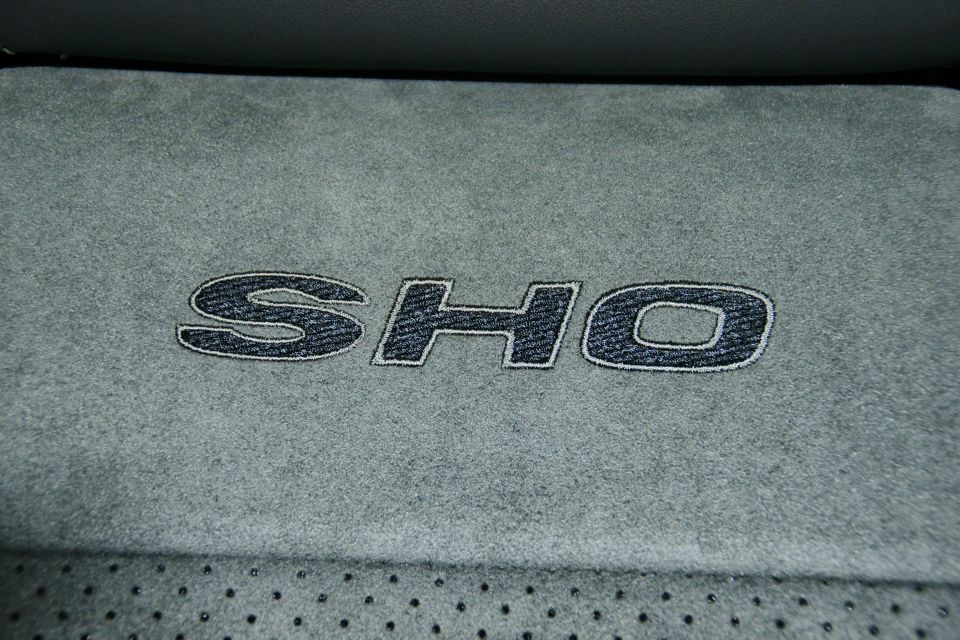 Embroidered SHO emblem on gray car seat upholstery with perforated sections