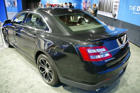 1993 Ford Taurus - Rear 3/4 view of a black sedan, identified as a Taurus by its badging, displayed at an auto show.