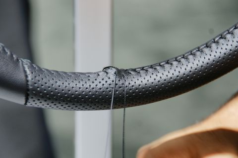 1993 Ford Taurus - A close-up view shows a black perforated steering wheel undergoing a stitching process.