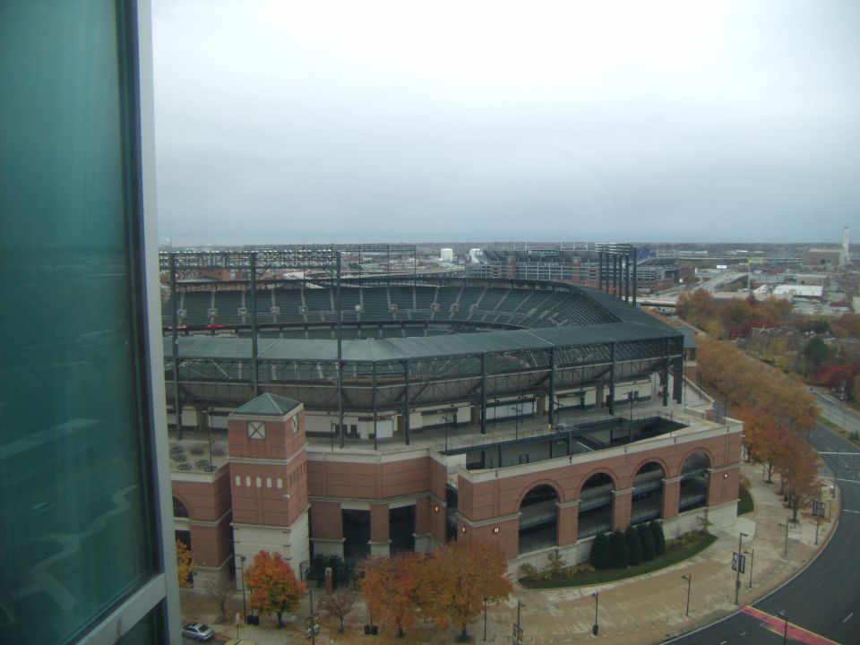 View of a stadium and surrounding cityscape on an overcast day. Watermark reads SUPERMOTORS.NET