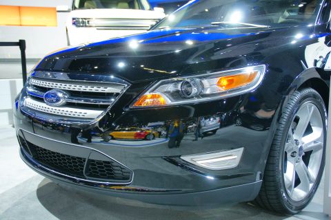 1993 Ford Taurus - A black Ford sedan is displayed at an auto show, with its grille and headlights prominently visible.
