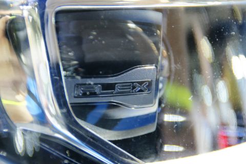 1993 Ford Taurus - A close-up view of a vehicle's "FLEX" emblem, set against a reflective chrome background.