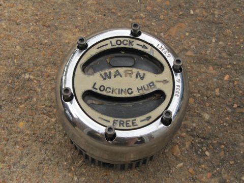 1995 Ford Bronco - A chrome Warn locking hub is shown resting on a concrete surface, with text indicating its lock and free positions.