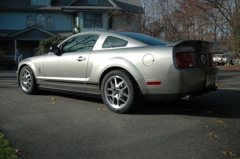 2008 Ford Mustang - Rear 3/4 view of a silver 2008 Ford Mustang Shelby GT500 with black racing stripes.