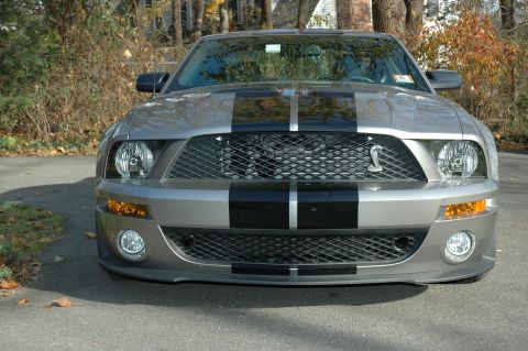 2008 Ford Mustang - Front view of a silver Ford Mustang with black racing stripes, parked outdoors.