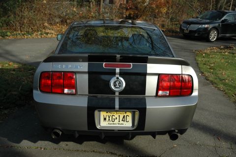 2008 Ford Mustang - Silver Ford Mustang Shelby GT500 with racing stripes and New Jersey plates. Another vehicle is parked behind it.