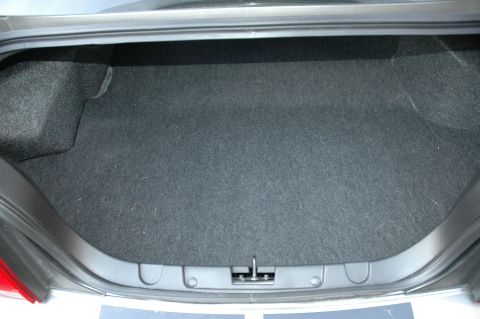 2008 Ford Mustang - The empty trunk of a car is shown, lined with dark grey carpet and a central latch.