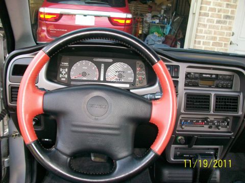 1999 Isuzu Vehicross - Interior view of an Isuzu with a custom steering wheel and a red SUV in the background.
