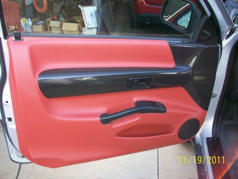 1999 Isuzu Vehicross - Interior door panel with red upholstery and black trim details is visible, alongside a red vehicle in the background.
