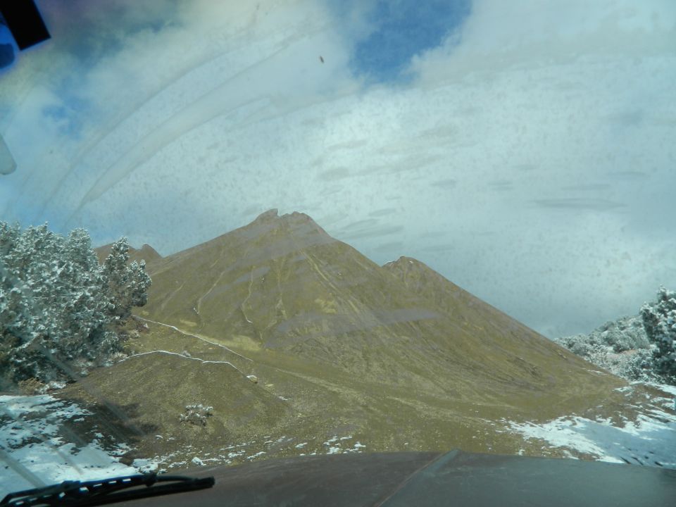 Mountain landscape with snow and trees seen through a dirty windshield