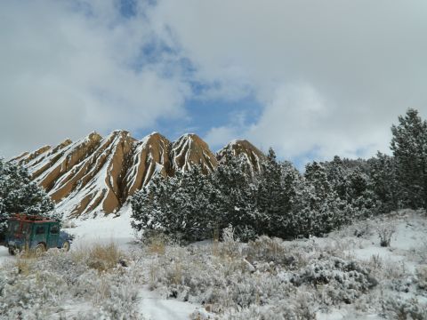 1979 Ford Bronco - A vintage SUV sits in a snowy landscape with prominent rock formations and pine trees.