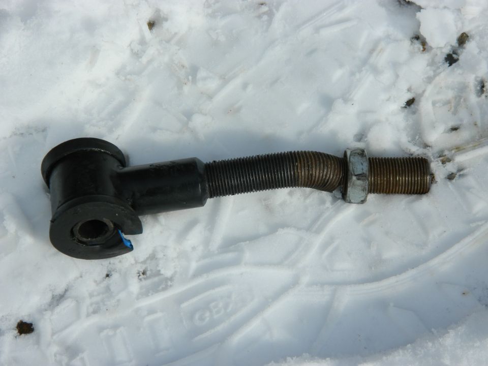 black metal suspension part with threaded rod and nut on snow