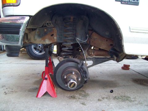 1996 Ford Bronco - The rear suspension of a 1996 Ford Bronco XLT is elevated on jack stands, revealing lift components and the brake system.