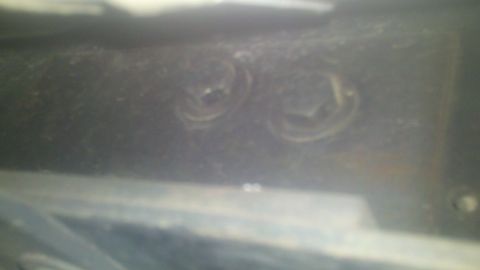 1988 Ford Bronco - Close-up view of two bolts on a dark surface, with no discernible vehicle details.