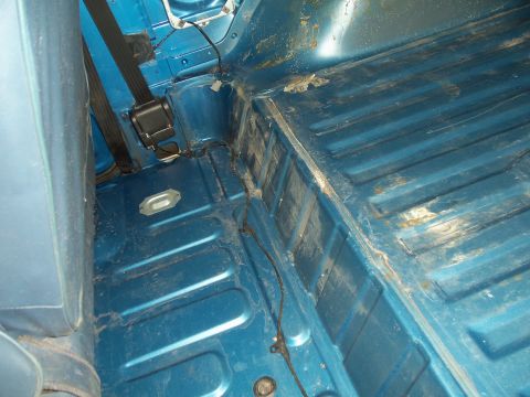 1985 Ford Bronco - The interior floor of the vehicle shows blue paint, seatbelt anchors, and signs of wear and tear.