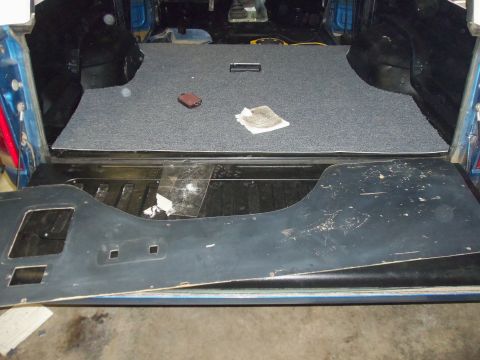 1985 Ford Bronco - The interior cargo area of a vehicle shows new gray carpeting and a removed black trim panel, with a "Supermotors.net" watermark at the bot…