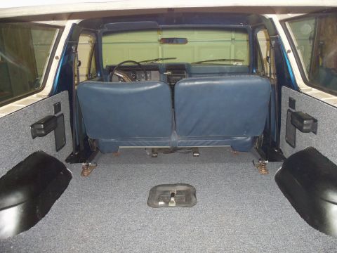 1985 Ford Bronco - The interior of a blue and white SUV is shown from the rear, with a focus on the cargo space and seating.