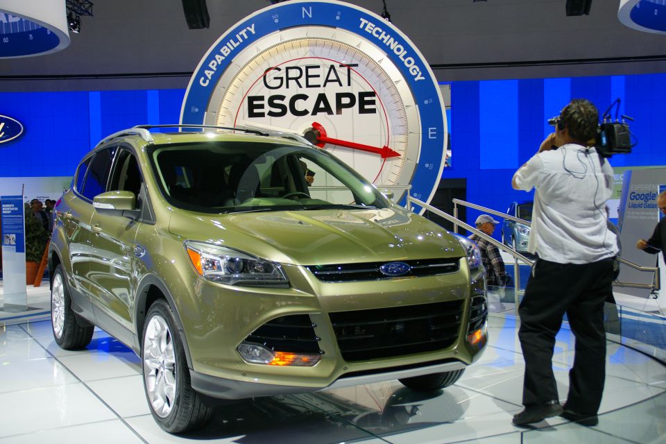 Green Ford SUV on display with a large circular sign behind it
