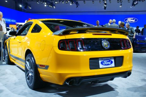 1993 Ford Taurus - A bright yellow Ford Mustang is displayed at an auto show, with another blue Ford visible in the background.