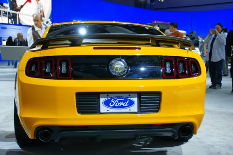1993 Ford Taurus - A yellow Ford Mustang is displayed at an auto show, with spectators in the background.