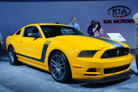 1993 Ford Taurus - A bright yellow 2012 Ford Mustang Boss 302 is displayed at an auto show, distinctive black racing stripes and side graphics.