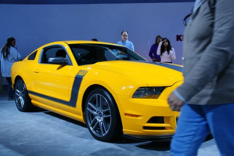1993 Ford Taurus - Yellow 2012 Ford Mustang Boss 302 on display at an auto show.