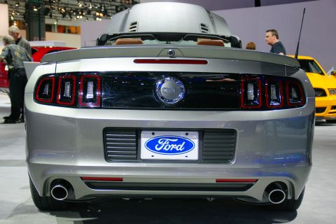 1993 Ford Taurus - The rear of a silver Ford Mustang is displayed at an auto show, with a yellow car visible in the background.