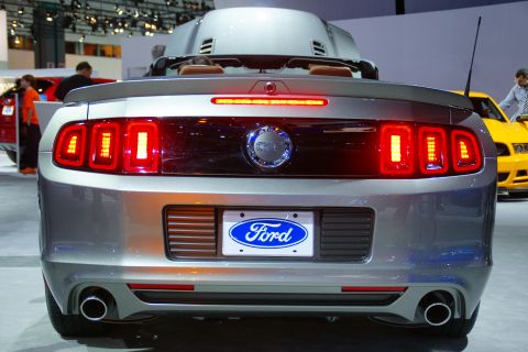 1993 Ford Taurus - Rear view of a silver Ford Mustang convertible at an auto show, with a yellow car in the background.