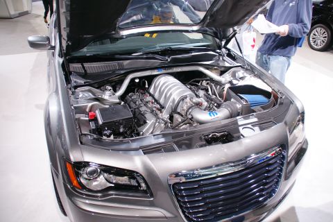1993 Ford Taurus - Engine bay of a grey car with the hood open, revealing a supercharged V8 engine and a prominent chrome grille.