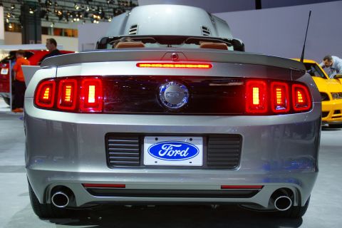 1993 Ford Taurus - Rear view of a silver Ford Mustang convertible, distinctive LED taillights and the iconic Ford emblem, displayed at an auto show.