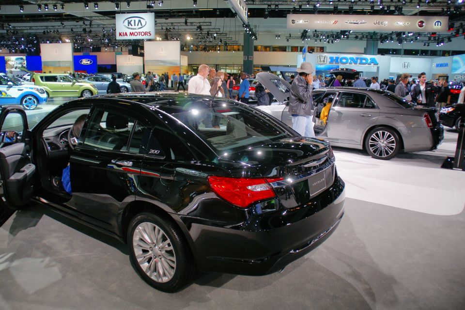 Black Chrysler 200 sedan with doors open at an auto show, silver Chrysler 300 behind it