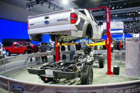 1993 Ford Taurus - A Ford F-150 Raptor is displayed on a rotary lift, showing its chassis and body separately at an auto show.