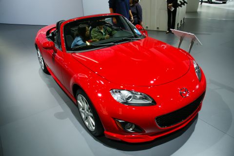 1993 Ford Taurus - A bright red convertible sports car is displayed at an auto show.
