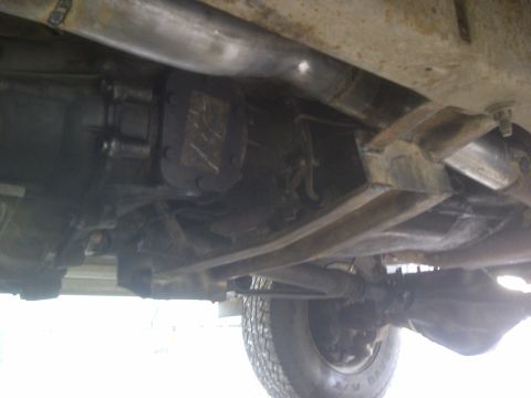 1979 Ford E250 - The underside of a vehicle, revealing its mechanical components and a portion of a tire.