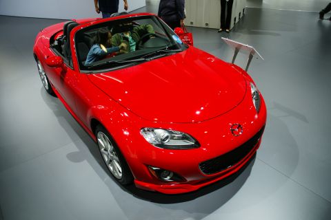 1993 Ford Taurus - A red convertible sports car is displayed indoors, possibly at an auto show.