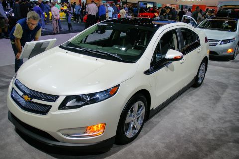 1993 Ford Taurus - White Chevrolet Volt on display at an auto show with a crowd in the background.