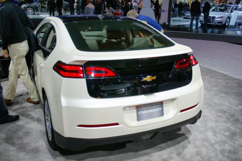 1993 Ford Taurus - The rear of a white Chevrolet Volt is displayed at an auto show, with people in the background.