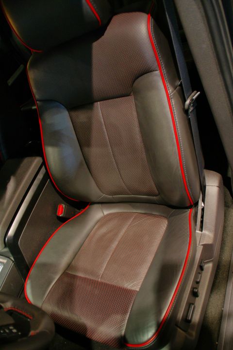 1993 Ford Taurus - Close-up of a car's interior seat, showing dark leather and red trim details.