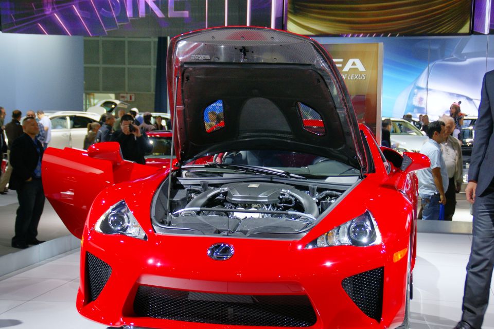 Red sports car front view, hood open showing engine. Lexus badge visible